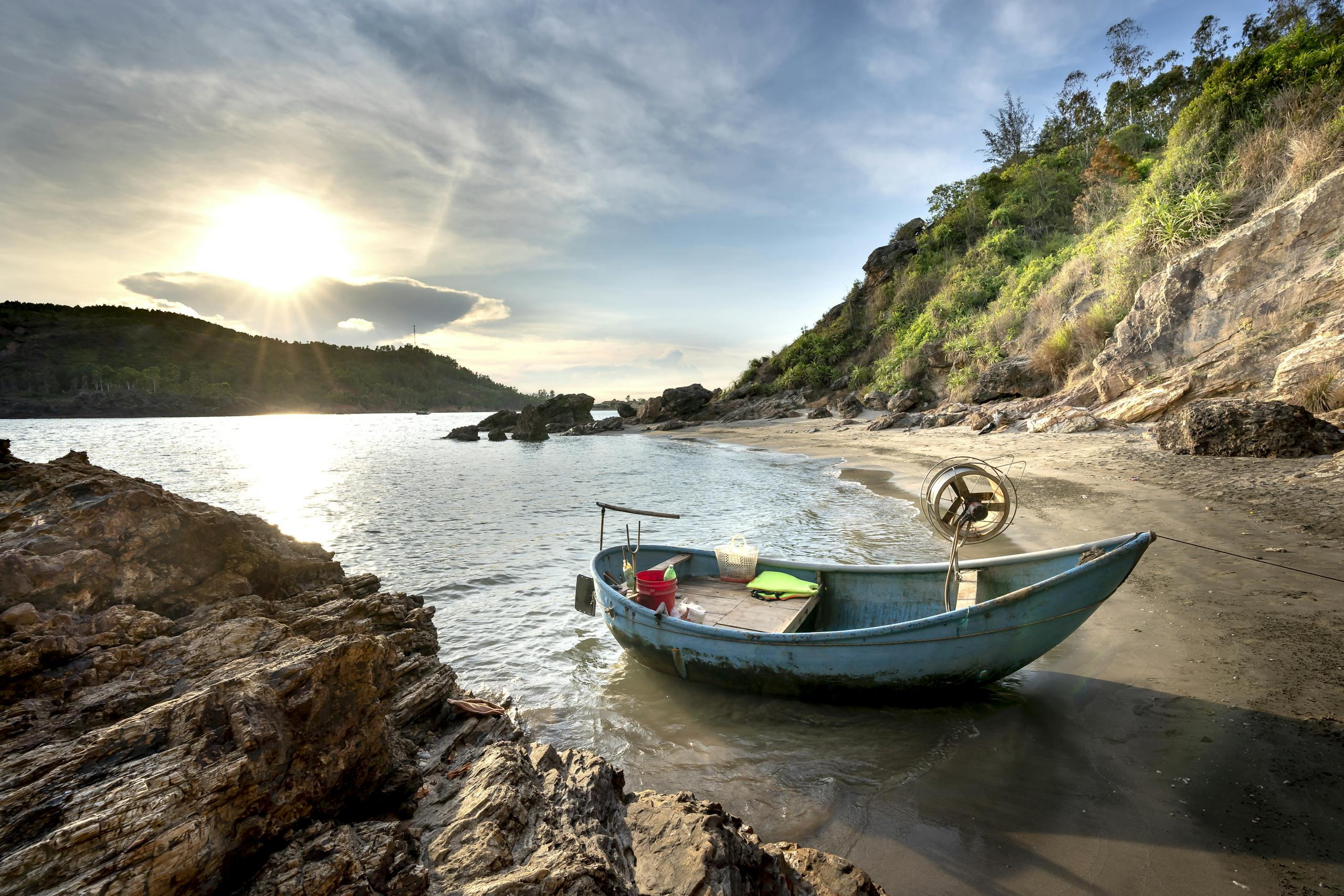 A picturesque small boat rests on a tranquil beach with a stunning sunset view.